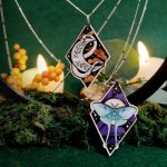 Detalle de collares de pendientes de madera con polilla lunar sobre cielo estrellado, serpiente sobre luna creciente